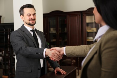 Photo of Smiling notary shaking hands with client in office