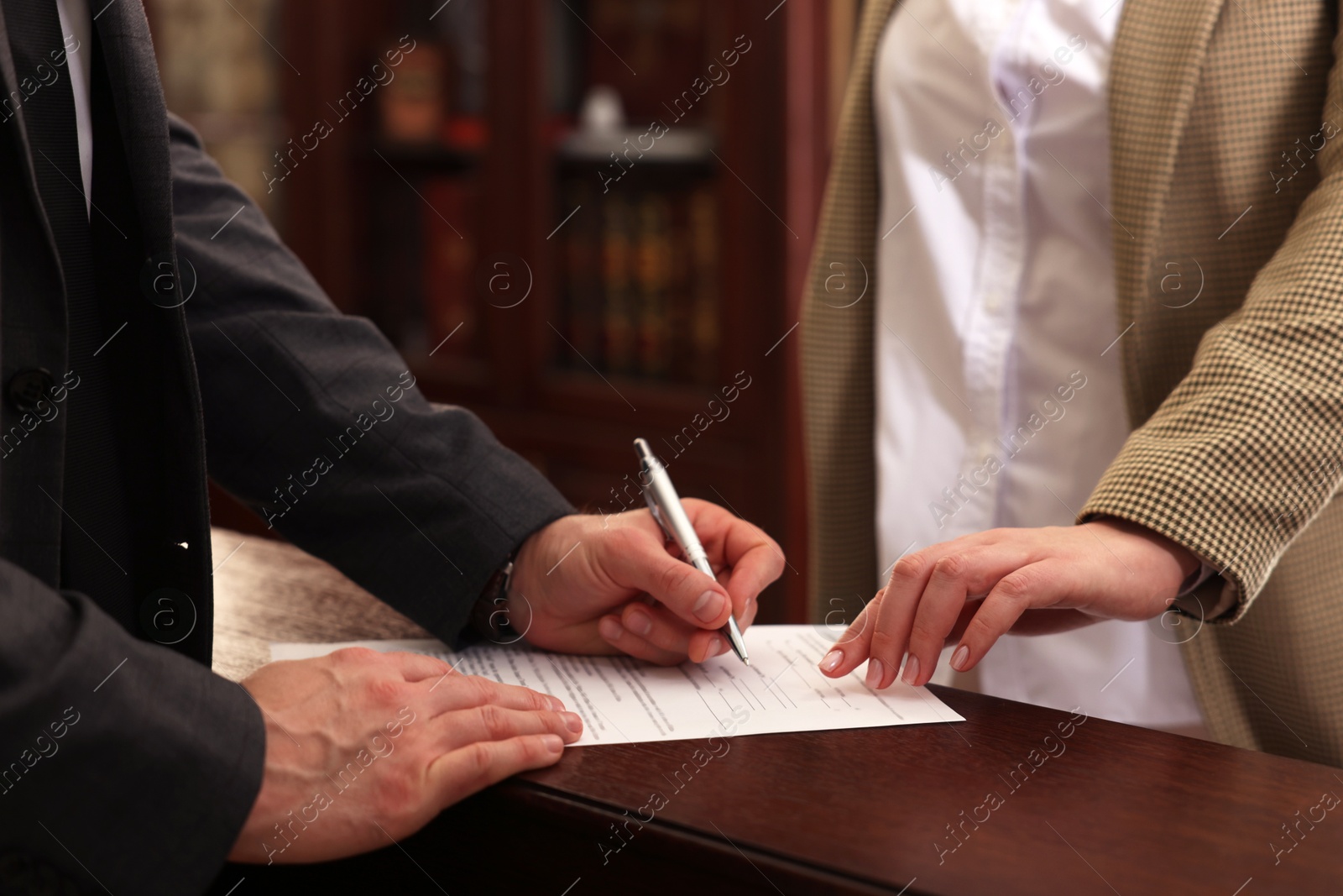 Photo of Notary showing client where to sign document in office, closeup