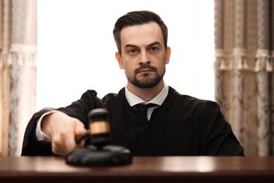 Photo of Judge striking gavel at table in courtroom