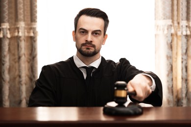 Photo of Judge striking gavel at table in courtroom