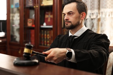 Photo of Judge striking gavel at table in courtroom