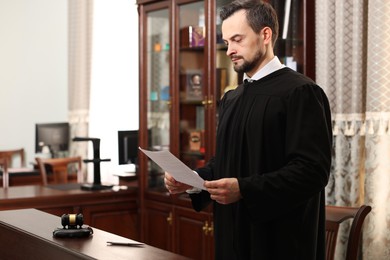 Photo of Judge with document at wooden table in courtroom