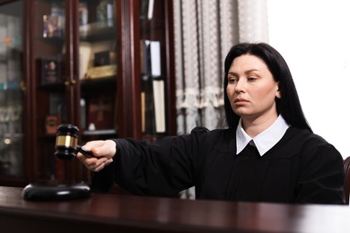 Photo of Judge striking gavel at wooden table in courtroom