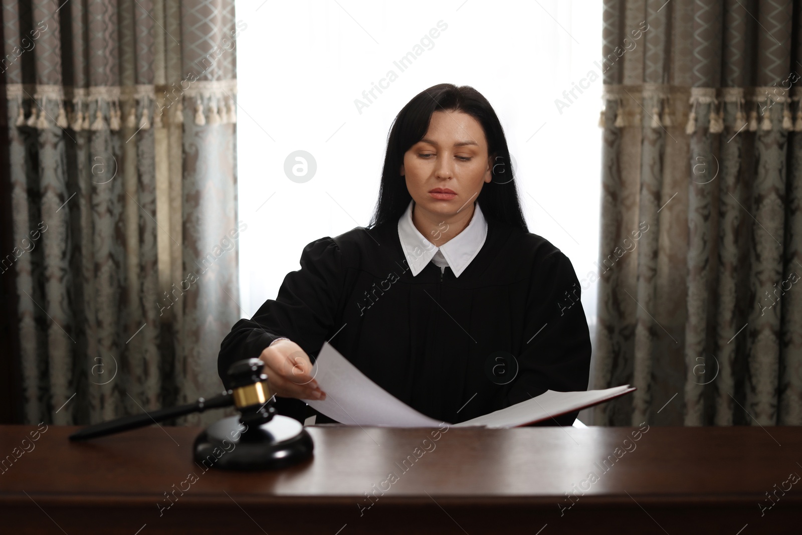 Photo of Judge with documents at wooden table in office