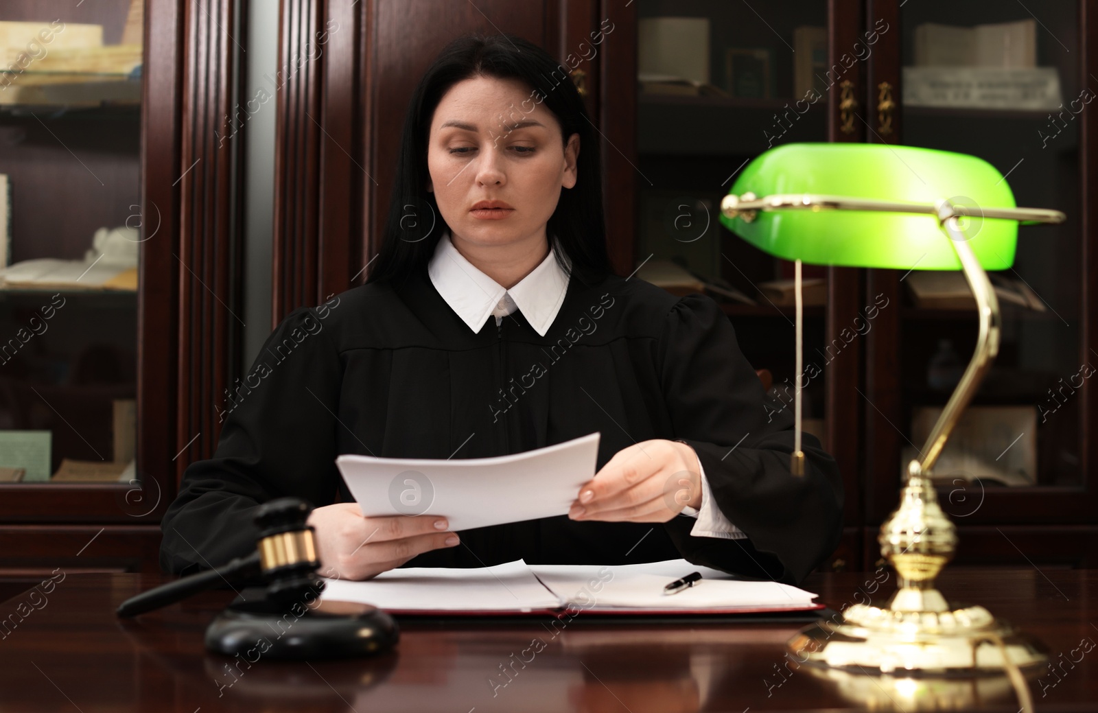 Photo of Judge working with documents at wooden table in office