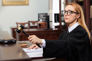 Judge striking gavel at table in courtroom