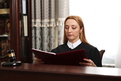 Judge with folder of documents at wooden table in courtroom