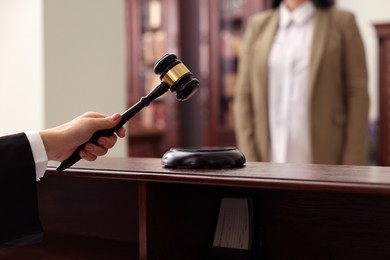 Photo of Judge striking gavel at wooden table in courtroom, closeup