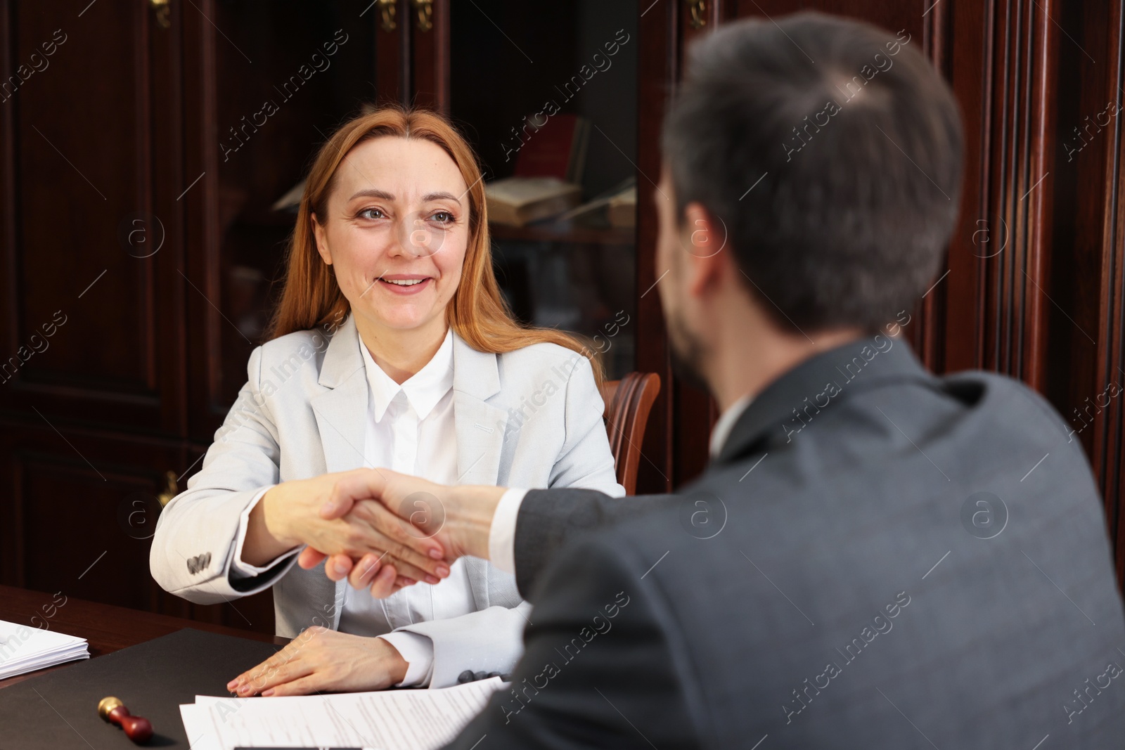 Photo of Smiling notary shaking hands with client in office