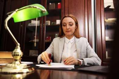 Photo of Notary stamping document at table in office