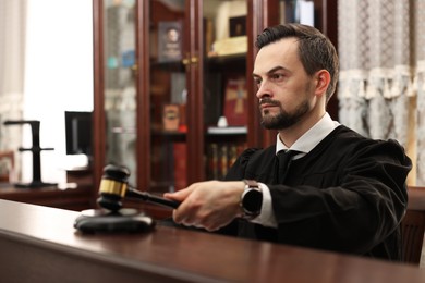 Photo of Judge striking gavel at table in courtroom