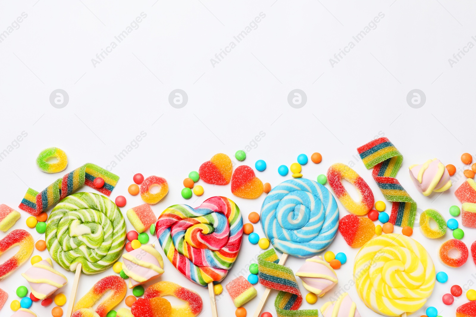 Photo of Many different tasty candies and marshmallows on white background, flat lay. Space for text