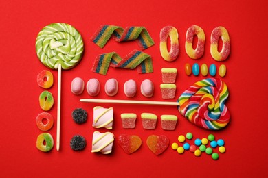 Different delicious candies and marshmallows on red background, flat lay