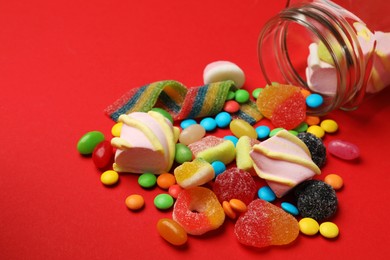 Photo of Different delicious candies and marshmallows on red background, closeup