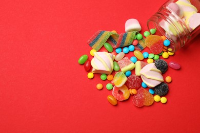 Photo of Different delicious candies and marshmallows on red background, flat lay. Space for text