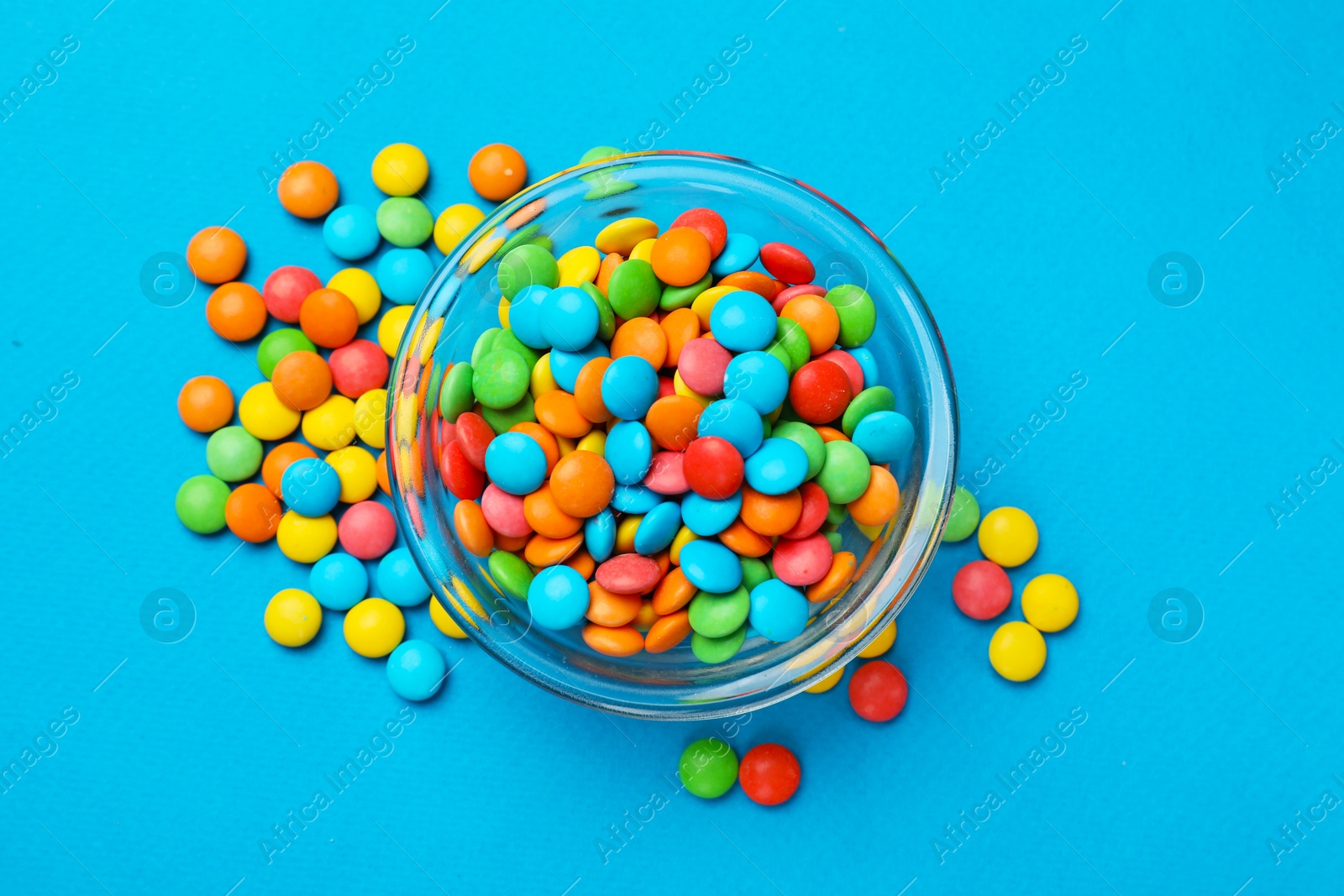 Photo of Colorful sugar coated dragee candies on blue background, top view