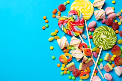 Different delicious candies and marshmallows on blue background, flat lay. Space for text