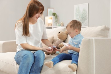 Photo of Mother and son playing with toy pyramid on sofa indoors