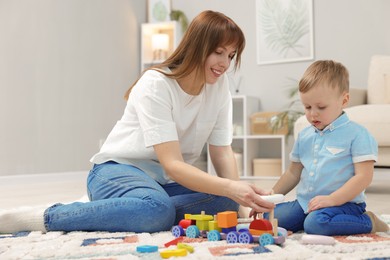 Photo of Mother and son playing with toys on floor at home