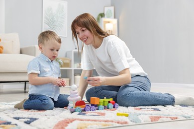 Photo of Mother and son playing with toys on floor at home