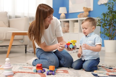 Photo of Mother and son playing with toys on floor at home