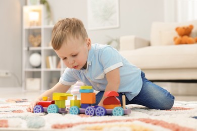 Photo of Little boy playing with toy train on floor indoors