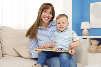 Photo of Mother and son playing with xylophone on sofa at home