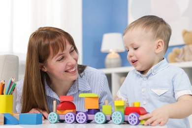 Photo of Mother and son playing with toys at table indoors