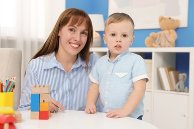 Photo of Mother and son playing with toys at table indoors