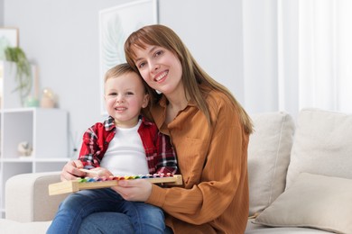 Photo of Mother and son playing with xylophone on sofa at home