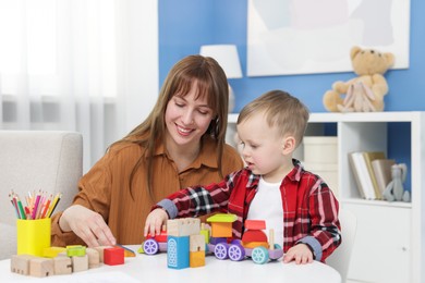 Photo of Mother and son playing with toys at table indoors