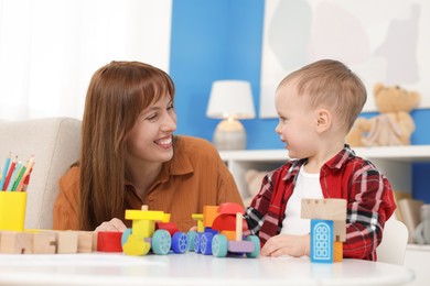 Photo of Mother and son playing with toys at table indoors