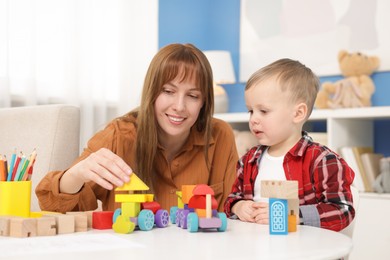 Photo of Mother and son playing with toys at table indoors