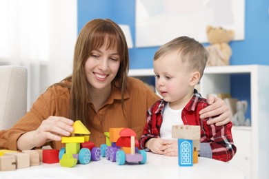 Photo of Mother and son playing with toys at table indoors