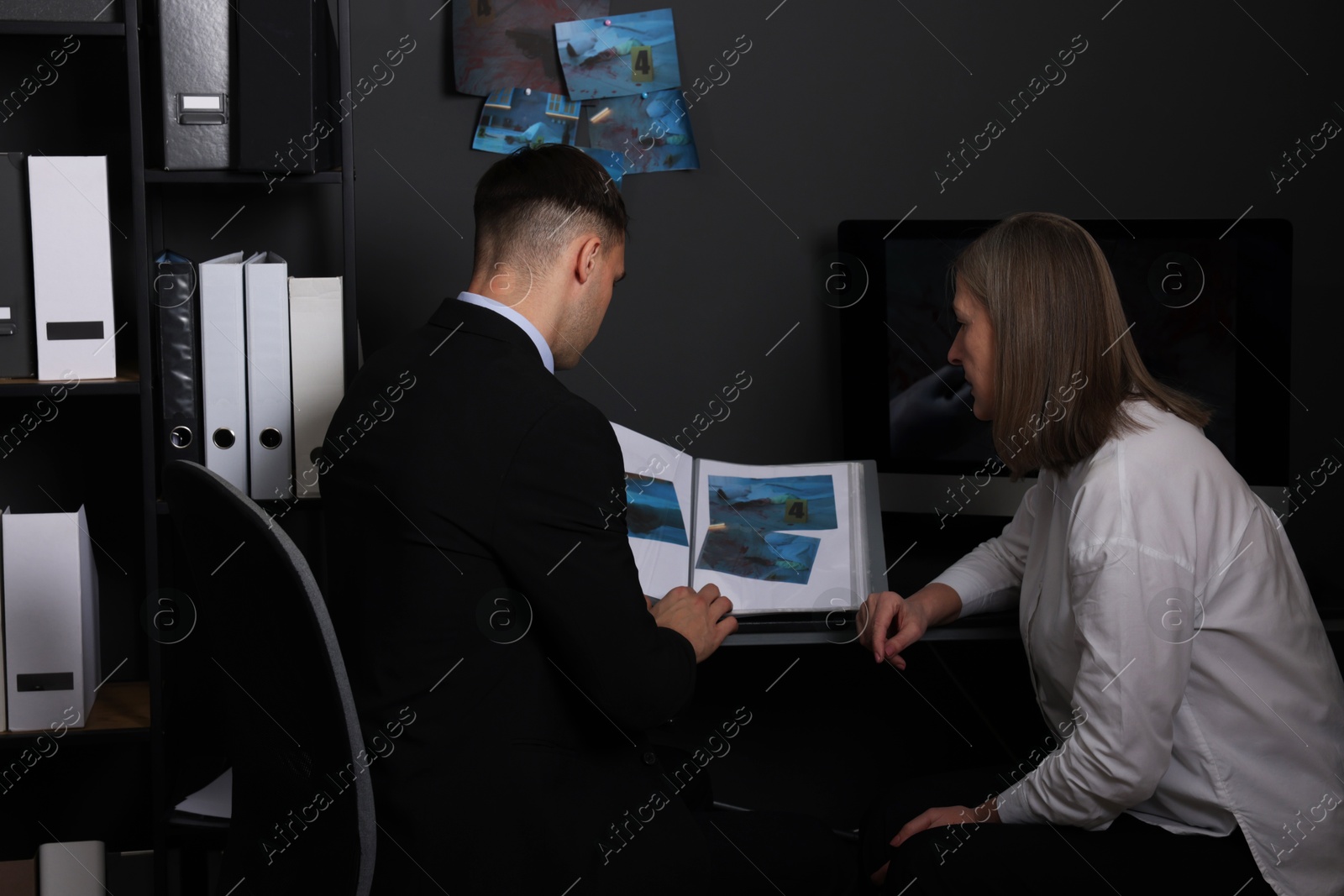 Photo of Forensic experts working with crime scene photos in office