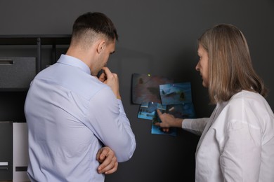 Forensic experts working with crime scene photos in office, back view