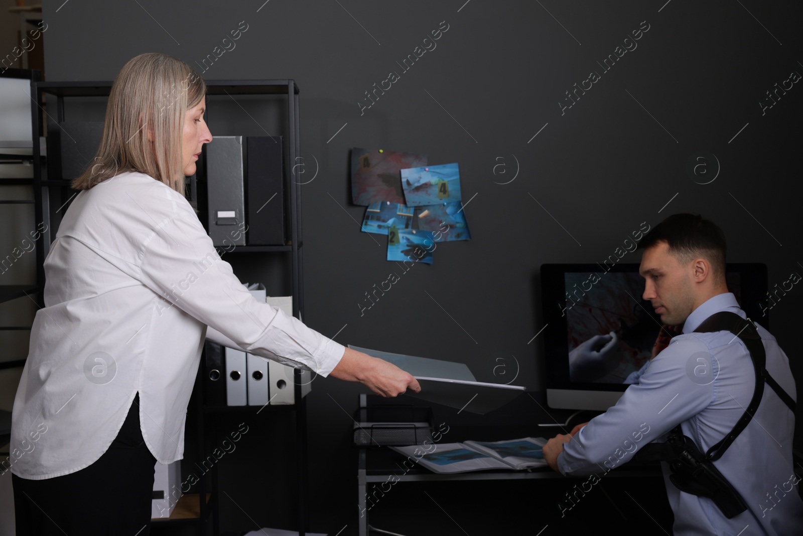 Photo of Forensic experts working with crime scene photos in office