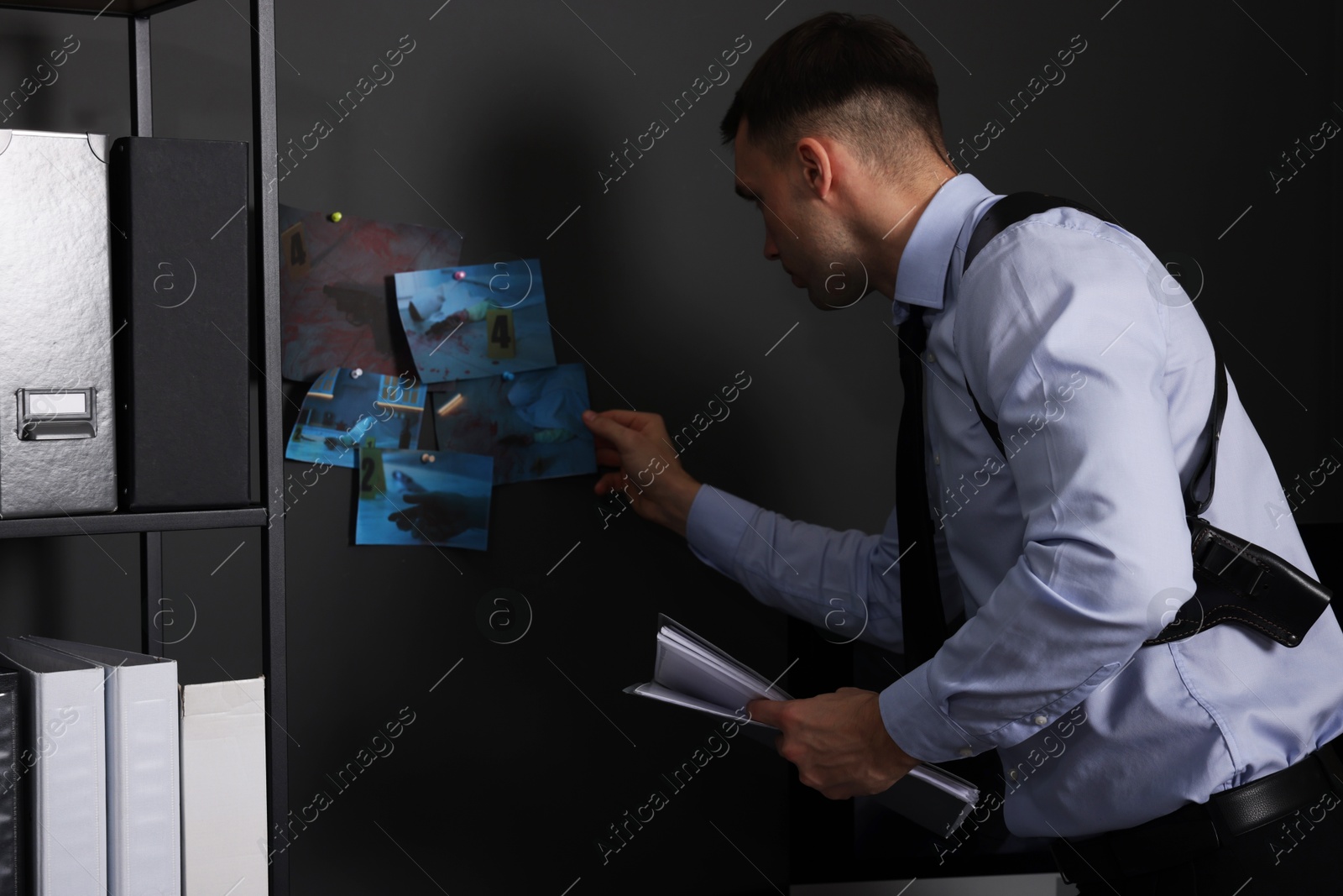 Photo of Forensic expert working with crime scene photos in office