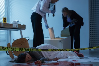 Forensic experts working at crime scene with dead woman's body indoors, selective focus