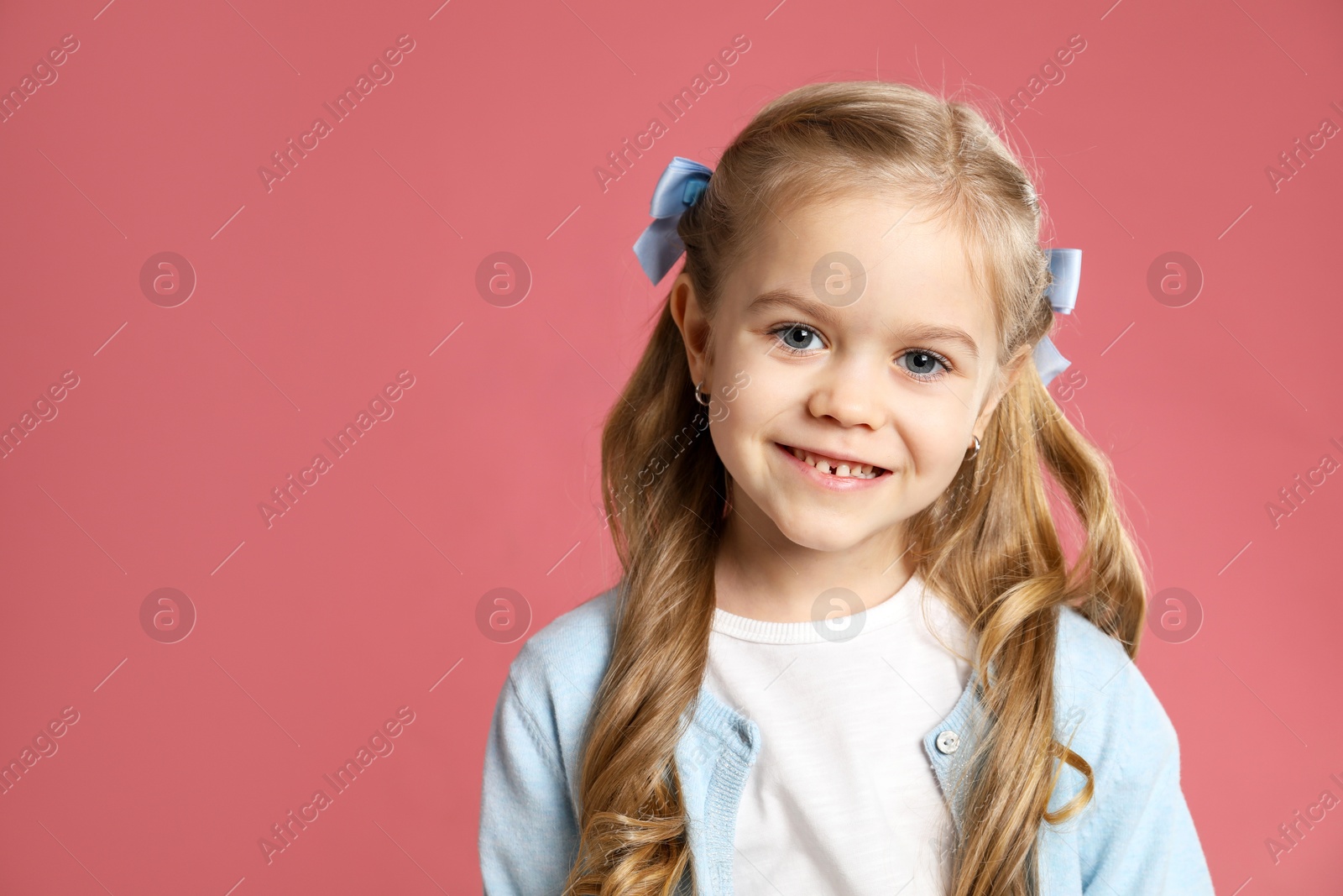 Photo of Cute little girl with beautiful hair accessory on coral background. Space for text