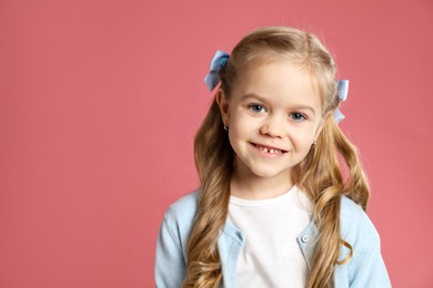 Photo of Cute little girl with beautiful hair accessory on coral background. Space for text