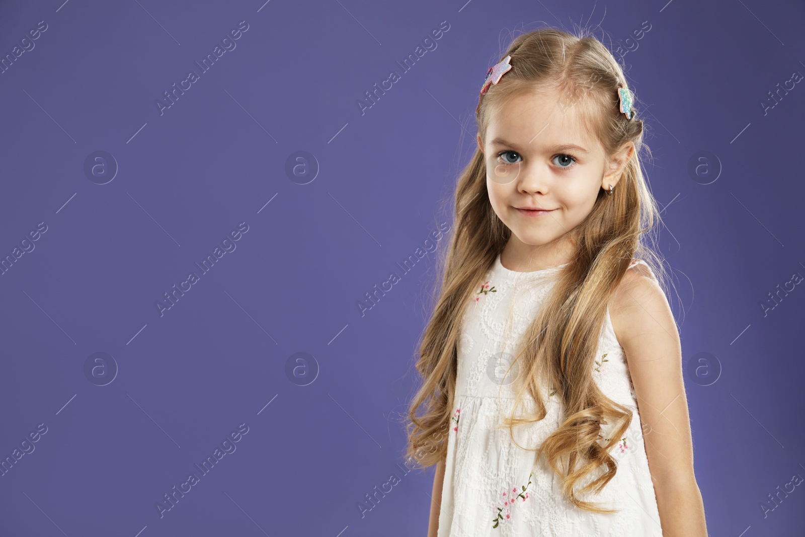 Photo of Cute little girl with beautiful hair clips on violet background. Space for text