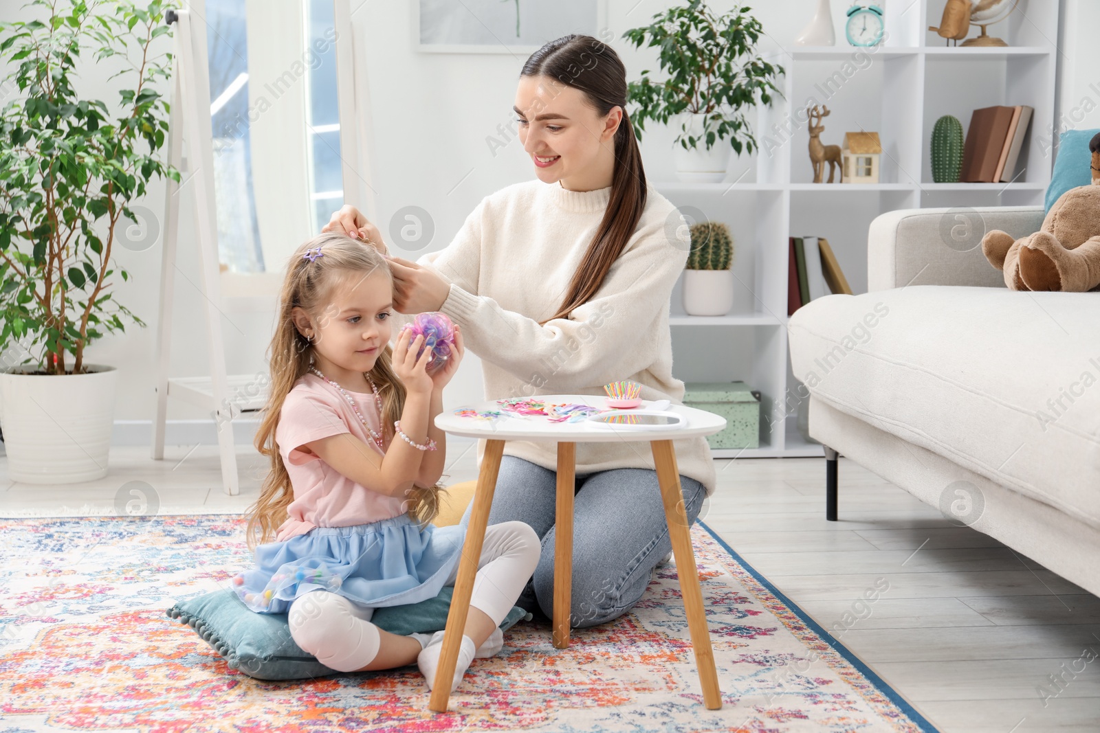 Photo of Mom putting cute accessories onto her daughter's hair at home