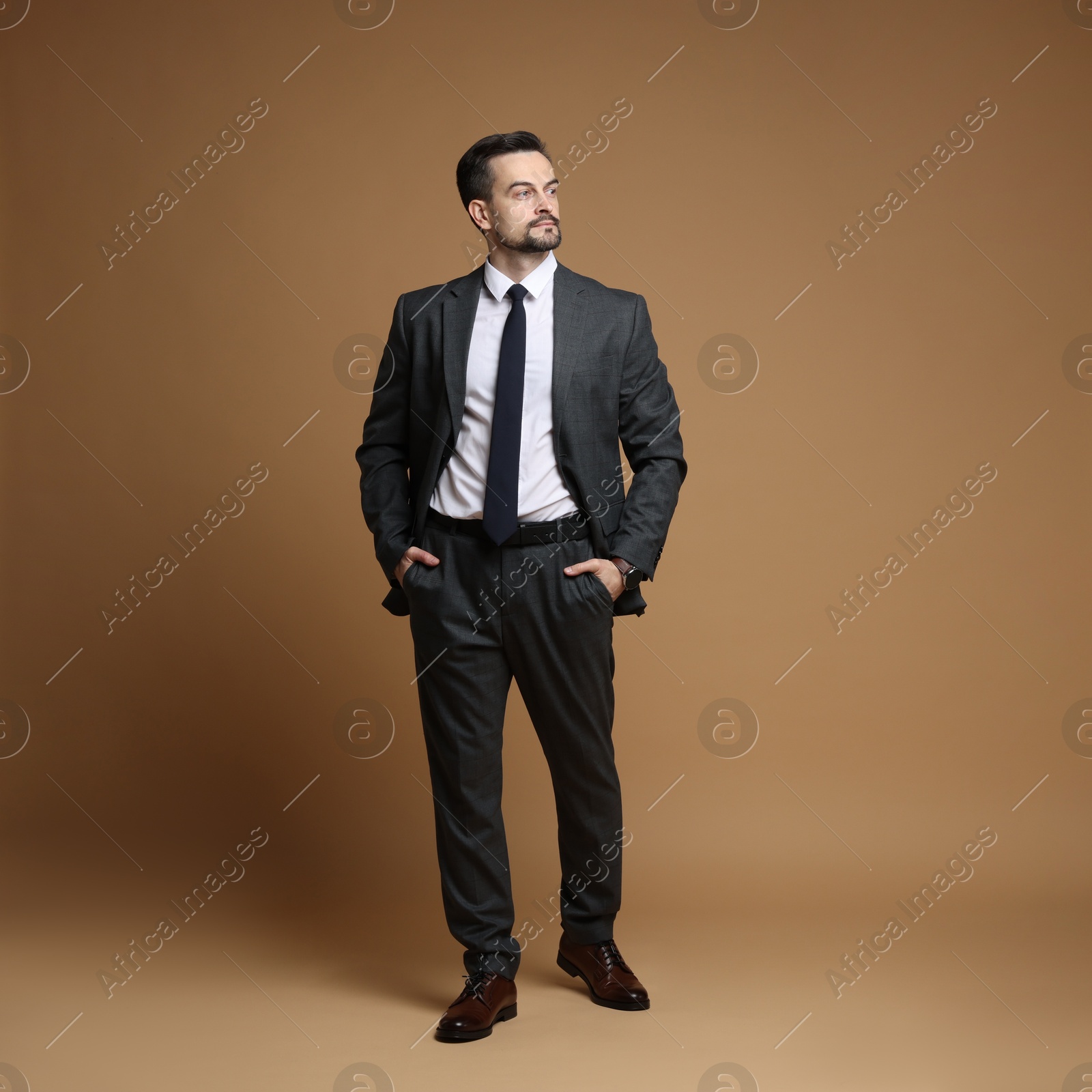 Photo of Confident man in classic suit on brown background