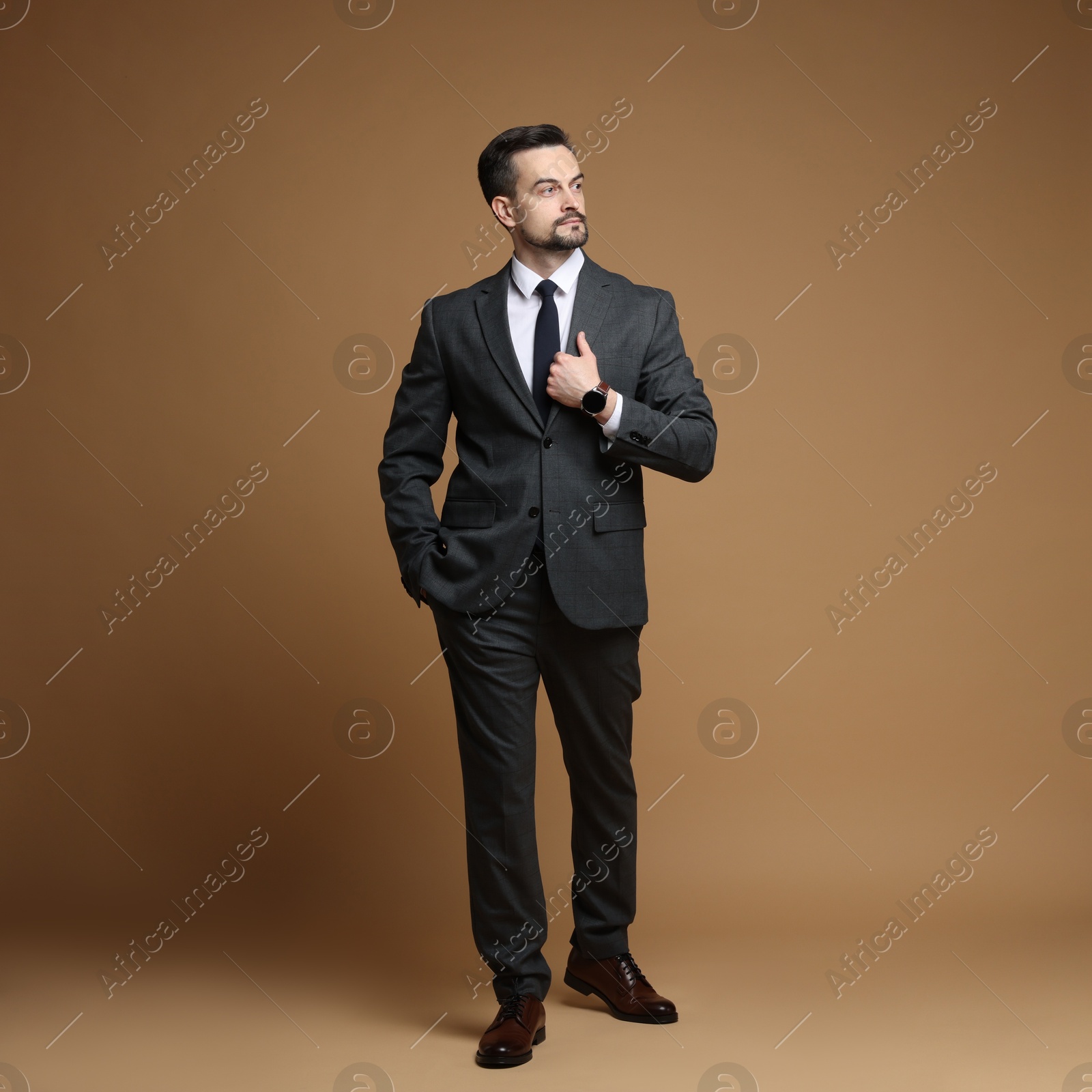 Photo of Confident man in classic suit on brown background