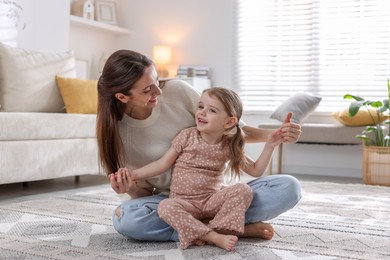 Photo of Happy mother with her cute little daughter on carpet at home