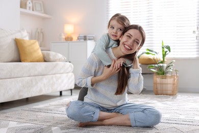 Photo of Happy mother with her cute little daughter on carpet at home