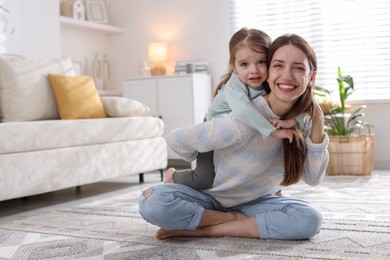 Photo of Happy mother with her cute little daughter on carpet at home