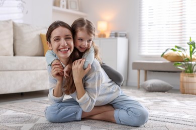 Photo of Happy mother with her cute little daughter on carpet at home