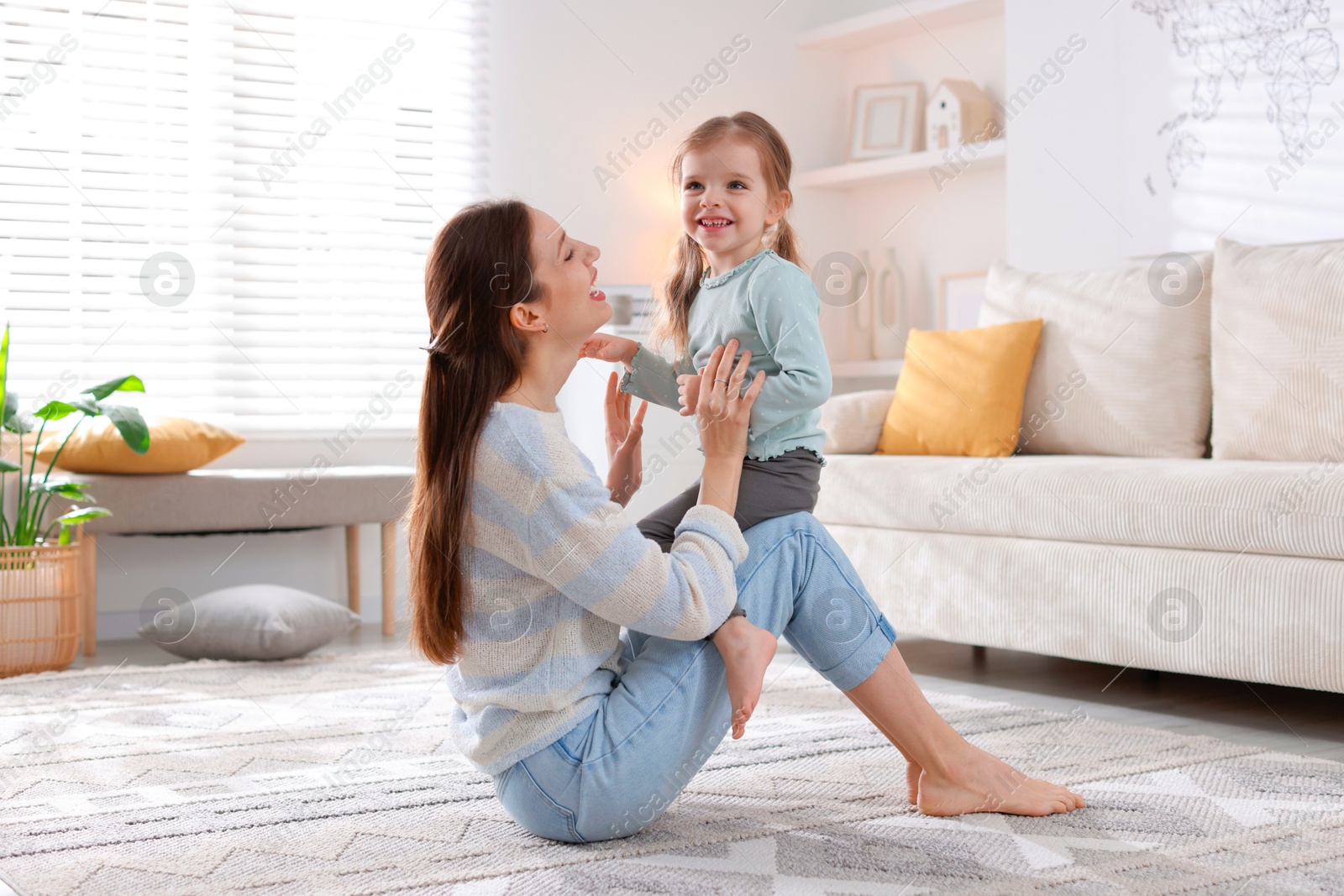 Photo of Happy mother with her cute little daughter on carpet at home